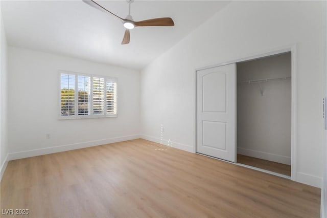 unfurnished bedroom with lofted ceiling, a closet, baseboards, light wood-style floors, and ceiling fan
