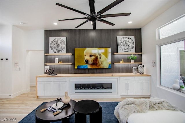 living area featuring light wood finished floors, an accent wall, ceiling fan, and recessed lighting