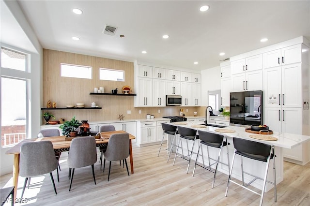 kitchen featuring visible vents, a kitchen breakfast bar, stainless steel microwave, recessed lighting, and black refrigerator