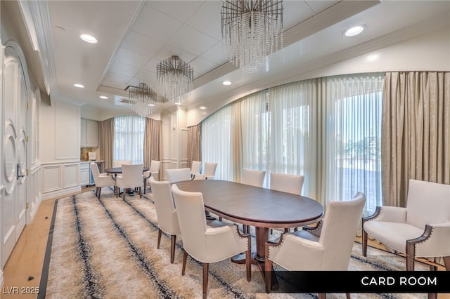 dining room with a chandelier, crown molding, a raised ceiling, and recessed lighting