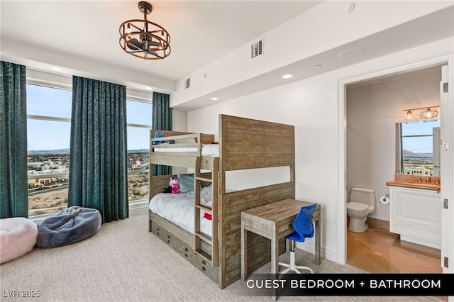 bedroom with ensuite bath, visible vents, recessed lighting, and a chandelier