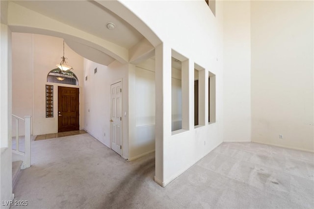 853 Ashford Way, Henderson, NV 89015 - hallway featuring light carpet, arched walkways, high vaulted ceiling, and stairs