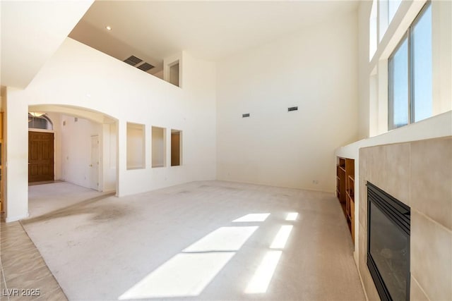 853 Ashford Way, Henderson, NV 89015 - unfurnished living room with a tiled fireplace, arched walkways, plenty of natural light, and a towering ceiling