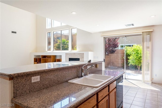 853 Ashford Way, Henderson, NV 89015 - kitchen with visible vents, a sink, dishwashing machine, brown cabinets, and a fireplace