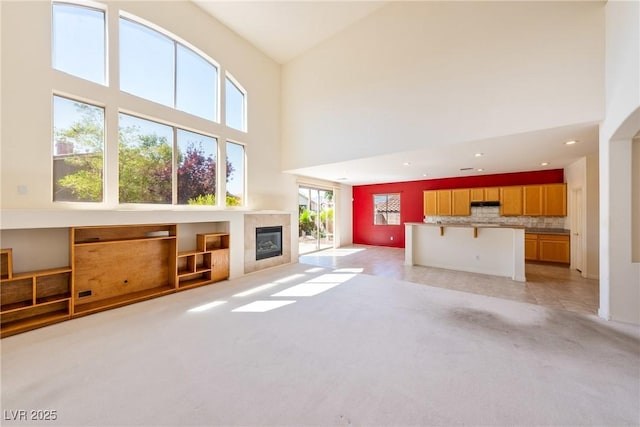 853 Ashford Way, Henderson, NV 89015 - unfurnished living room with light carpet, a high ceiling, recessed lighting, and a tile fireplace