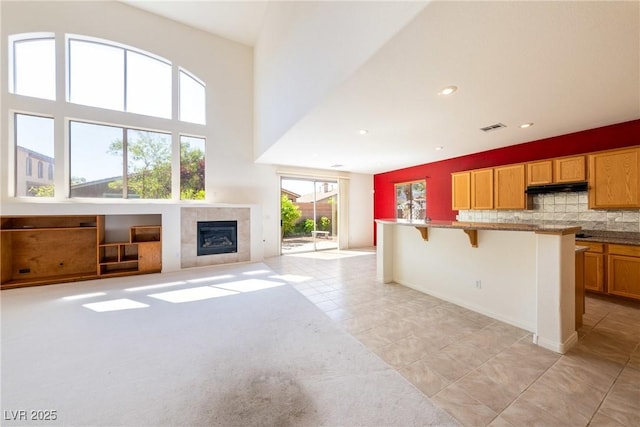 853 Ashford Way, Henderson, NV 89015 - unfurnished living room with visible vents, light tile patterned floors, a tiled fireplace, recessed lighting, and a towering ceiling