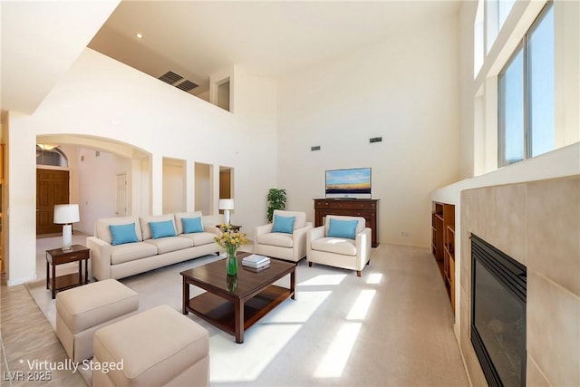 853 Ashford Way, Henderson, NV 89015 - living room with arched walkways, a tile fireplace, visible vents, and a high ceiling