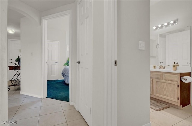 6480 Annie Oakley Dr Unit 511, Las Vegas, NV 89120 - hallway featuring arched walkways, light tile patterned flooring, baseboards, and a sink