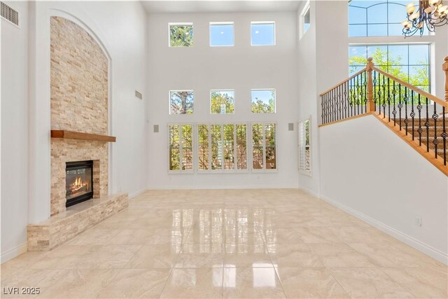 2285 Villefort Ct, Las Vegas, NV 89117 - unfurnished living room featuring a chandelier, a towering ceiling, a stone fireplace, stairs, and tile patterned floors