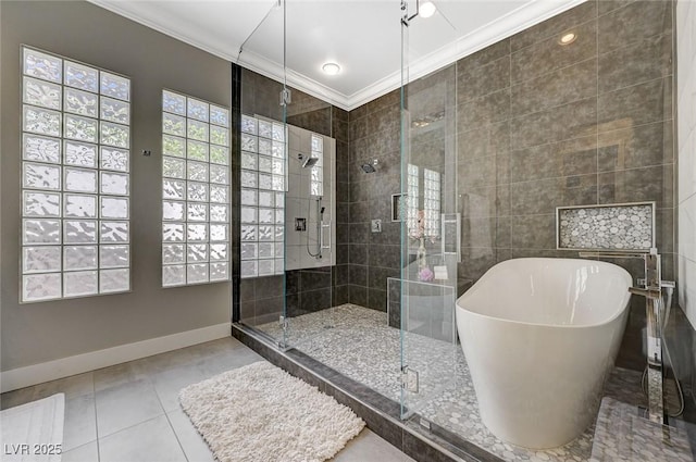 bathroom with baseboards, ornamental molding, a soaking tub, tile patterned floors, and a stall shower