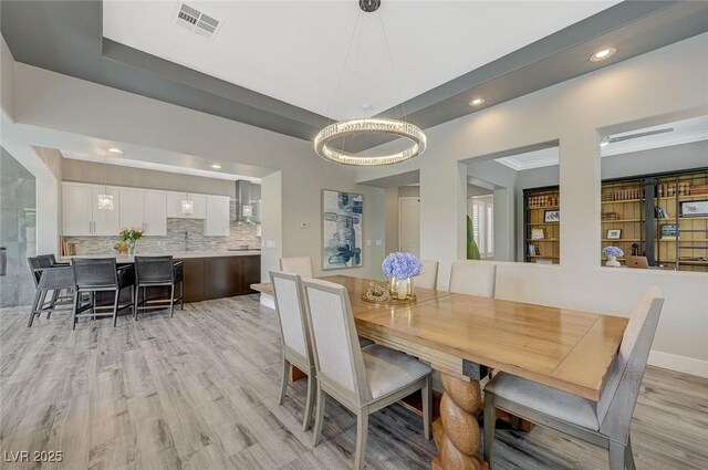dining area with visible vents, baseboards, a tray ceiling, light wood finished floors, and recessed lighting