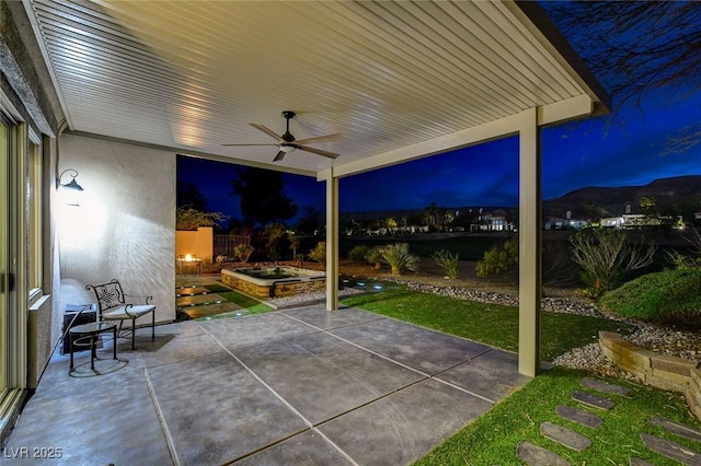 patio at night with fence and a ceiling fan