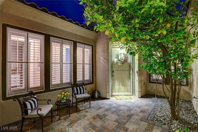 entrance to property with a patio area and stucco siding