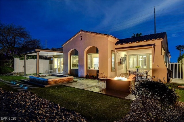 back of house featuring stucco siding, a fire pit, a patio area, a tile roof, and fence