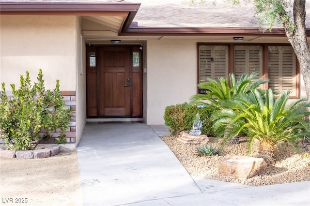 property entrance featuring stucco siding and roof with shingles