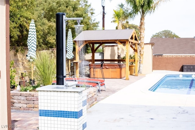 view of patio / terrace with fence, an outdoor pool, a gazebo, and a hot tub