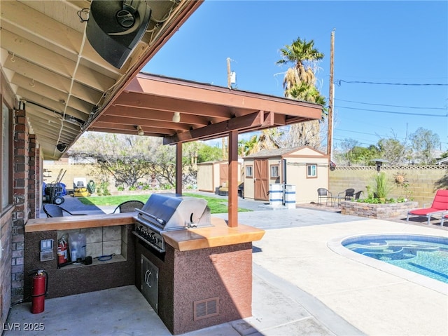 view of patio with a fenced backyard, an outdoor structure, an outdoor kitchen, visible vents, and area for grilling
