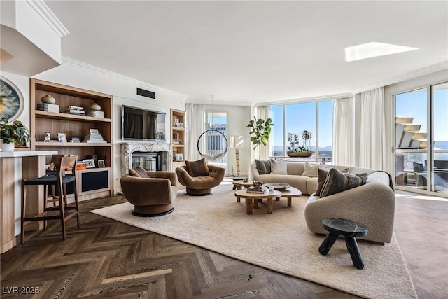 living area with crown molding, built in shelves, and a glass covered fireplace