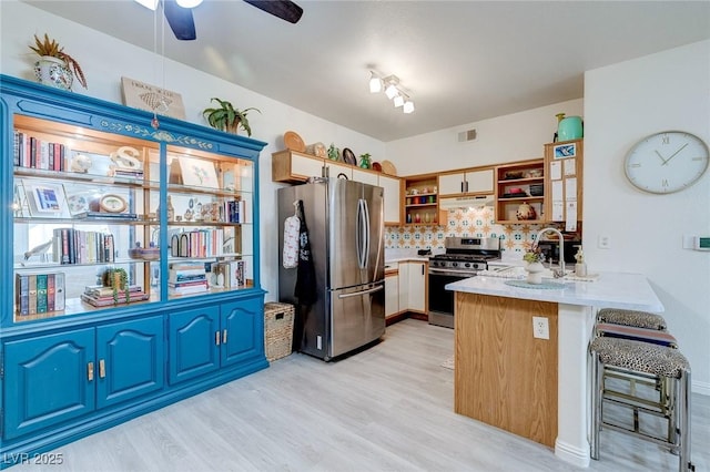 kitchen with a peninsula, open shelves, stainless steel appliances, backsplash, and light countertops