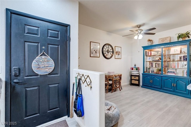 entryway featuring wood finished floors, baseboards, and ceiling fan