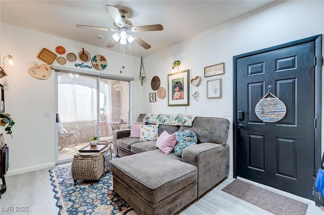 living area featuring baseboards, a ceiling fan, and wood finished floors