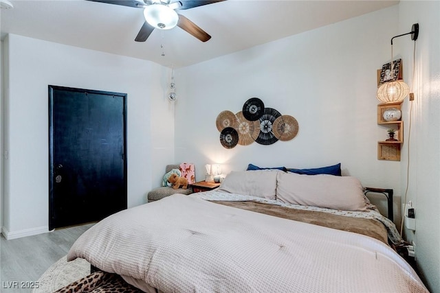 bedroom featuring baseboards, light wood finished floors, and ceiling fan
