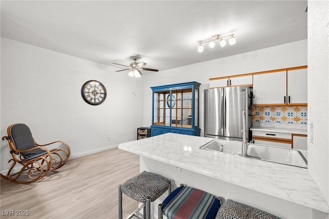 5751 Hacienda Ave Unit 135, Las Vegas, NV 89122 - kitchen featuring freestanding refrigerator, a sink, a breakfast bar, light wood-style flooring, and light countertops