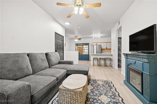 5751 Hacienda Ave Unit 135, Las Vegas, NV 89122 - living area with ceiling fan, light wood finished floors, a glass covered fireplace, and baseboards