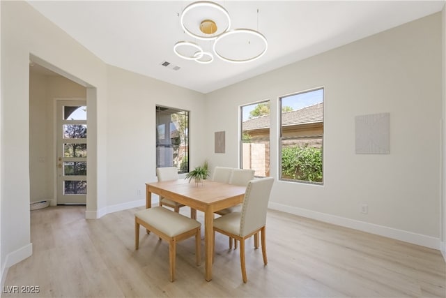 dining area featuring baseboards, light wood finished floors, and visible vents