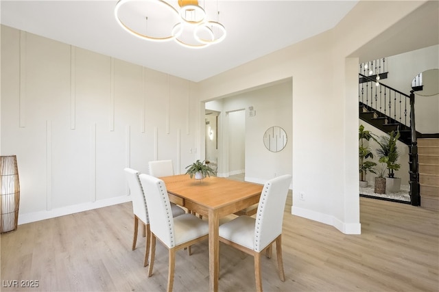 dining space with baseboards, stairway, an inviting chandelier, and light wood-type flooring