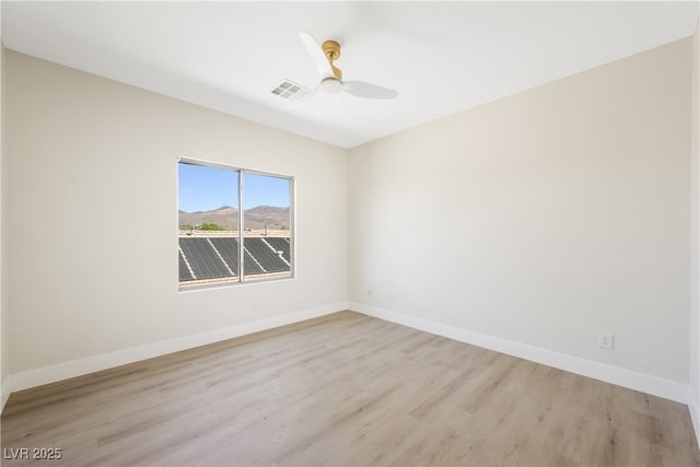 spare room with a ceiling fan, visible vents, light wood-style flooring, and baseboards
