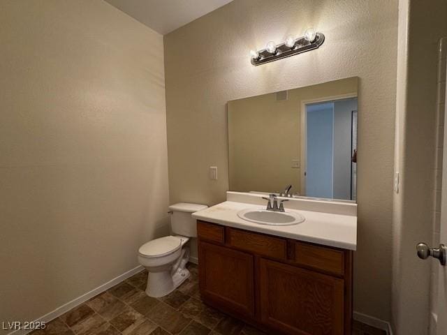 bathroom featuring toilet, vanity, and baseboards