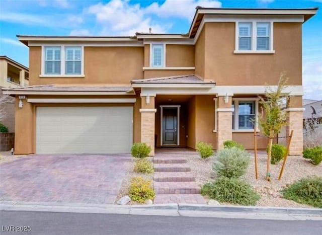 view of front of house featuring decorative driveway, a garage, and stucco siding