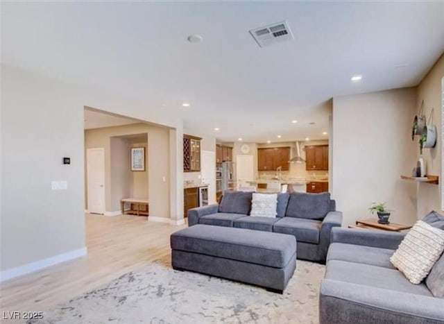 living room with visible vents, light wood-type flooring, recessed lighting, and baseboards