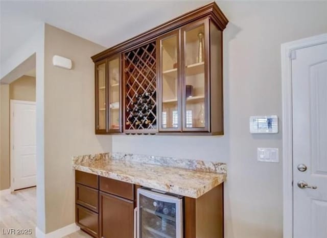 bar with wine cooler, a dry bar, baseboards, and light wood-style floors