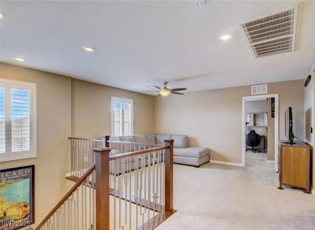 interior space featuring visible vents, baseboards, an upstairs landing, and carpet flooring