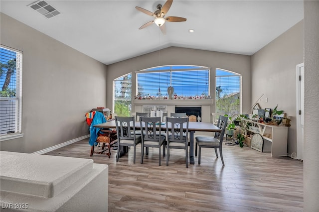 90 Ancient Hills Ln, Henderson, NV 89074 - dining area featuring wood finished floors, a ceiling fan, vaulted ceiling, a glass covered fireplace, and baseboards