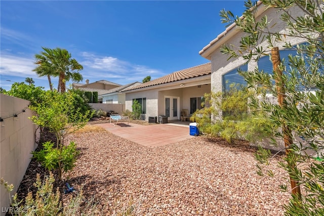 90 Ancient Hills Ln, Henderson, NV 89074 - rear view of house featuring french doors, a tiled roof, stucco siding, a fenced backyard, and a patio area