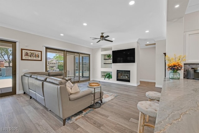 living area featuring ceiling fan, plenty of natural light, ornamental molding, and recessed lighting