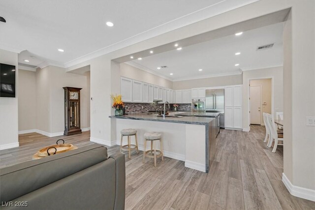 kitchen featuring white cabinetry, a peninsula, light wood-style floors, and a sink