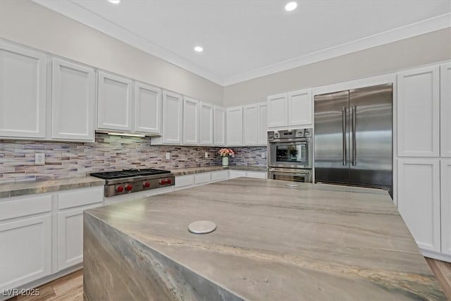 kitchen featuring backsplash, light stone countertops, white cabinets, and appliances with stainless steel finishes