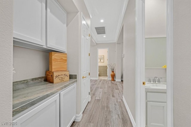 hallway with recessed lighting, a sink, visible vents, light wood-style flooring, and baseboards