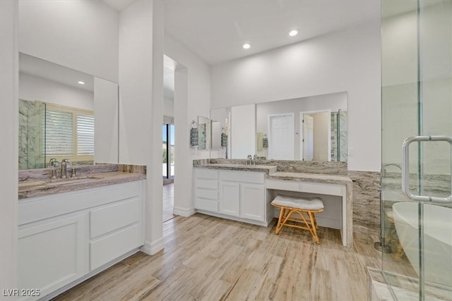 bathroom with recessed lighting, wood finished floors, two vanities, and a sink