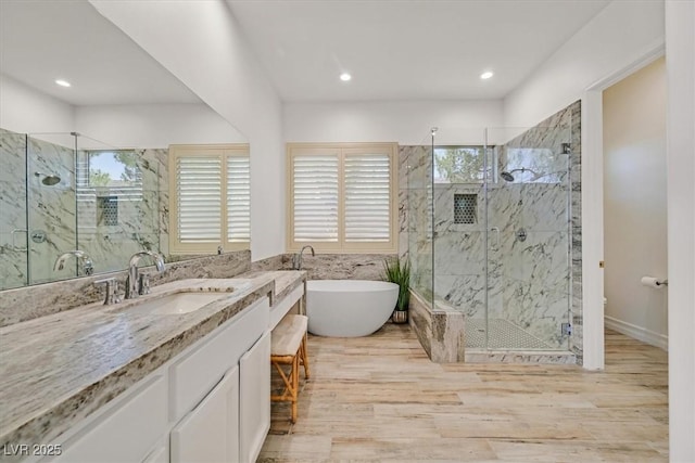 bathroom with recessed lighting, vanity, a marble finish shower, a soaking tub, and wood finished floors