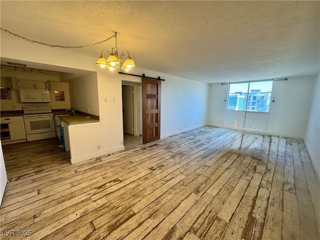 3930 University Center Dr Unit 409, Las Vegas, NV 89119 - unfurnished living room featuring a barn door, a textured ceiling, light wood-style flooring, a chandelier, and a sink