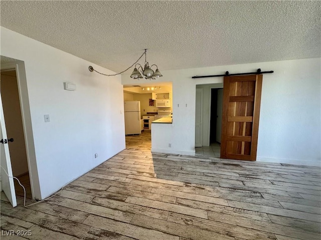 3930 University Center Dr Unit 409, Las Vegas, NV 89119 - unfurnished living room featuring a barn door, light wood-style flooring, a textured ceiling, and a chandelier