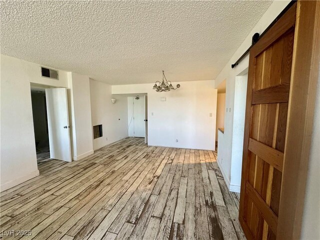 3930 University Center Dr Unit 409, Las Vegas, NV 89119 - spare room featuring wood finished floors, a textured ceiling, a chandelier, and a barn door