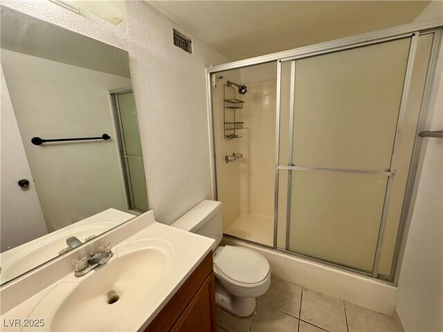 3930 University Center Dr Unit 409, Las Vegas, NV 89119 - full bathroom with a shower with shower door, toilet, tile patterned flooring, vanity, and a textured wall