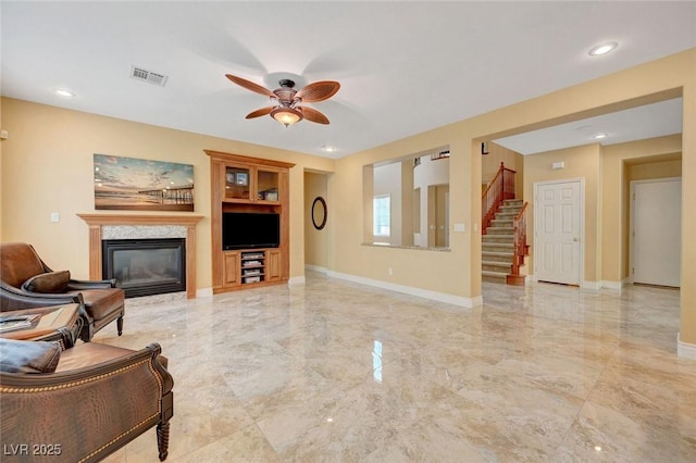 living area with visible vents, a ceiling fan, marble finish floor, and a glass covered fireplace