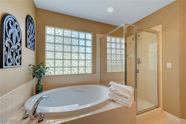 bathroom featuring a stall shower, a healthy amount of sunlight, and a garden tub